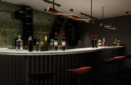 Kuma Club bar interior, Las Vegas gay bathhouse. Liquor bottles line the counter. Stylish lighting. Dark, modern design. Gay travel.