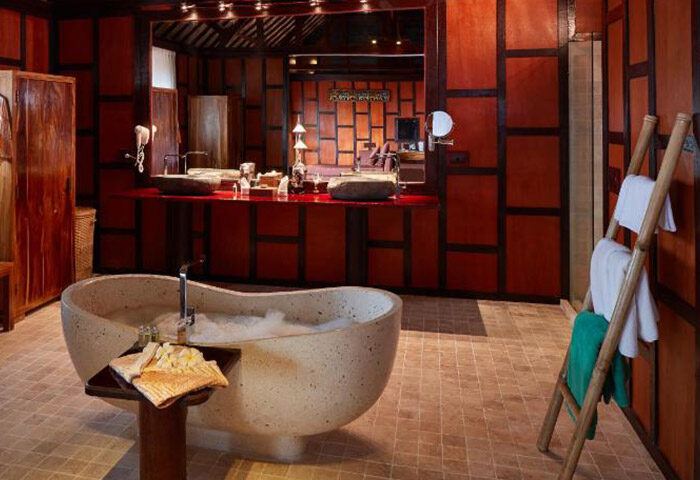 Luxury bathroom at Kupu Kupu Phangan Beach Villas & Spa by L’Occitane. Gay hotel with bathtub, red wood panels, and bamboo ladder.