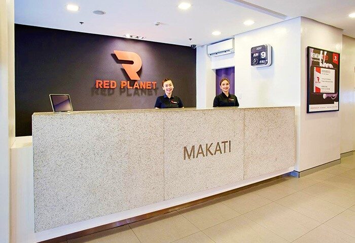 Red Planet Manila Makati lobby. LGBT-friendly hotel in a central location. Reception desk with staff. Modern design.