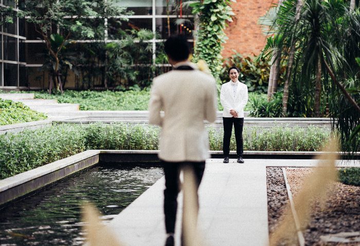 Gay wedding at Pullman Bangkok King Power. Groom awaits his partner in a garden setting. LGBTQ+ travel advice.