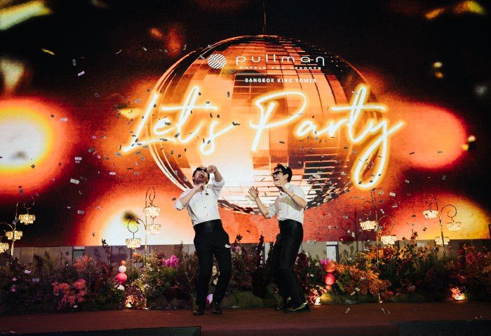 Gay wedding at Pullman Bangkok King Power. Two grooms celebrate under confetti and a disco ball. Let's Party in neon lights.