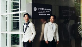 Gay wedding at Pullman Bangkok King Power. Two grooms in white tuxedos smile. LGBTQ wedding in Thailand. Gay travel advice.