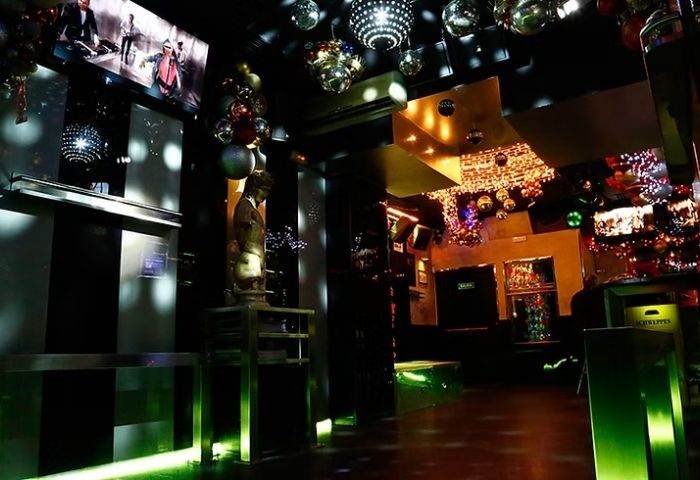 Interior of LL Bar, a gay bar in Madrid. Disco balls, festive decor, and a statue create a vibrant nightlife atmosphere. Gay travel advice.