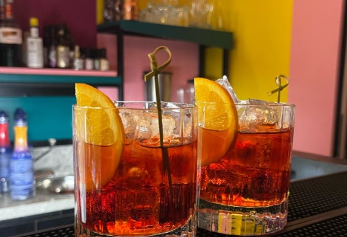 Milan's LOLA bar: Two Negroni cocktails with orange slices and ice. Gay travel advice for the best Milan bars and nightlife spots.