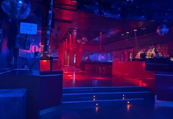 Interior of La Boite Gay Club in Madrid. Red and blue lights illuminate the dance floor and bar area. Gay travel destination.