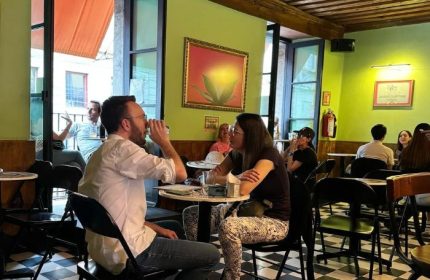 Patrons at La Botica Gay Bar in Mexico. A couple sits at a table, drinks in hand, enjoying the vibrant atmosphere. Gay travel.