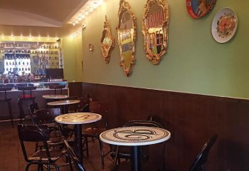 La Botica Gay Bar interior in Mexico. Tables, chairs, bar with bottles, ornate mirrors on the wall. Gay travel advice.