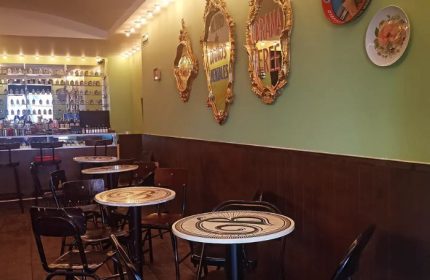 La Botica Gay Bar interior in Mexico. Tables, chairs, bar with bottles, ornate mirrors on the wall. Gay travel advice.