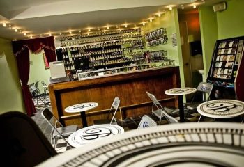 Interior of La Botica Gay Bar in Mexico. Tables, chairs, jukebox, and fully stocked bar. Gay travel advice for your next vacation.