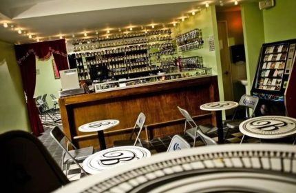 Interior of La Botica Gay Bar in Mexico. Tables, chairs, jukebox, and fully stocked bar. Gay travel advice for your next vacation.