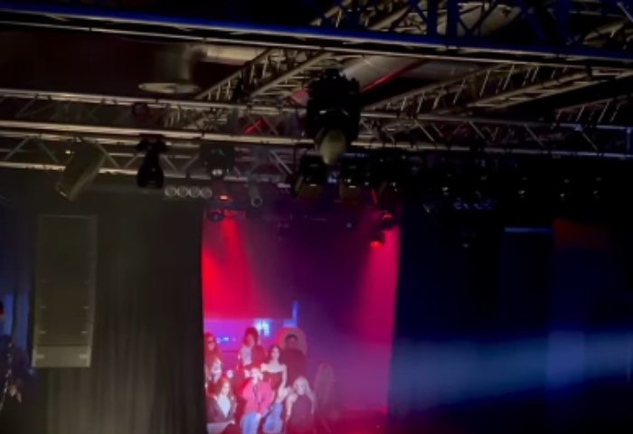 La Boum Milano stage view. Gay nightlife travel advice. Stage lighting, speakers, and a screen with people are visible. Gay club.
