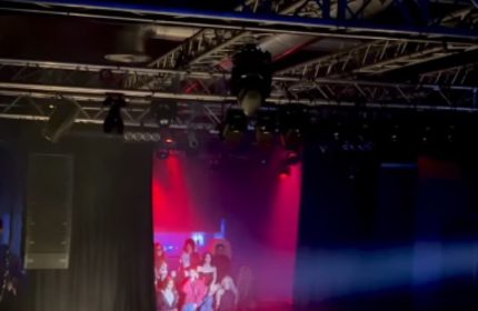 La Boum Milano stage view. Gay nightlife travel advice. Stage lighting, speakers, and a screen with people are visible. Gay club.