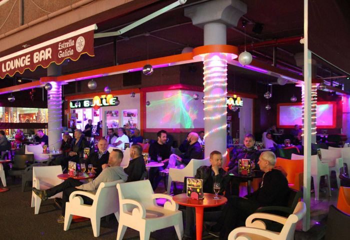 La Bulle Gay Bar in Gran Canaria. Men relax at tables in this lounge bar with disco balls and colorful lighting. Gay travel advice.