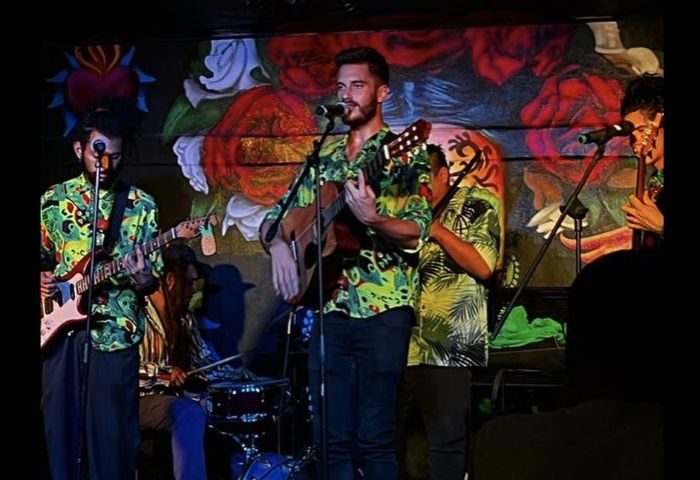 Live music at La Cantina Margarita gay bar in Puerto Vallarta. Band performing with guitars, drums, and colorful shirts. Nightlife.