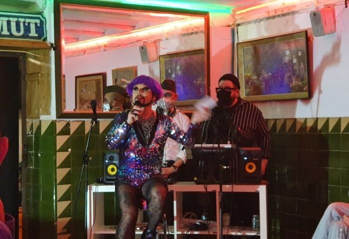 Drag queen performing at La Casa de la Pradera gay bar in Barcelona. Nightlife scene with audience and DJ. Gay travel advice.