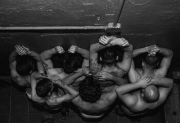 Black and white aerial view of shirtless men in La Casita CDMX gay bar, Mexico City. Tattoos visible on arms and back.