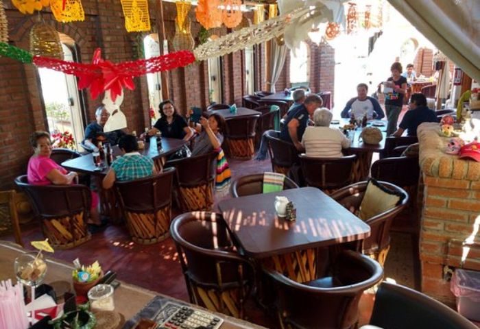La Catrina Cantina, a gay bar in Puerto Vallarta. People sit at tables in a festive atmosphere with colorful decorations overhead.
