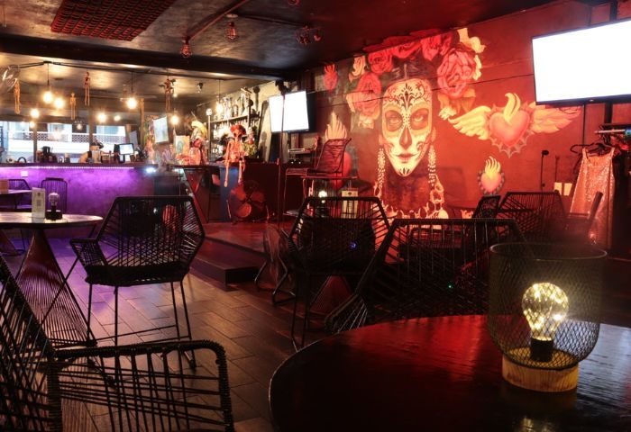 Interior of La Catrina Cantina, a gay bar in Puerto Vallarta. Features a mural of La Catrina and stylish seating. Nightlife vibe.