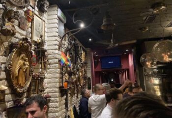 La Chapelle Gay Bar in Barcelona. Interior view with religious decor, rainbow flag, and patrons enjoying the gay nightlife scene.