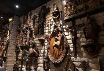 La Chapelle Gay Bar, Barcelona. Brick wall covered in religious iconography, crosses, statues of Jesus and Mary. Unique gay travel experience.