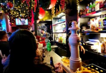Inside La Chapelle Gay Bar in Barcelona, men at the bar, TV screen showing a scantily clad man, Christmas decorations. Gay travel advice.