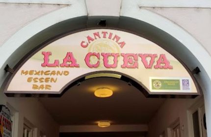 La Cueva Cantina sign in Puerto Vallarta. Gay bar entrance with 'Cantina La Cueva' in pink letters. Mexicano Essen Bar.