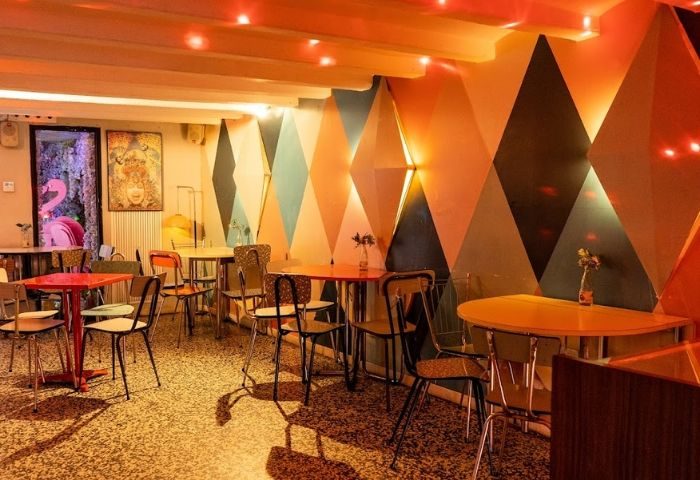 La Federica Gay Bar, Barcelona. Interior view with colorful geometric wall design, tables, chairs, and a pink flamingo decoration.
