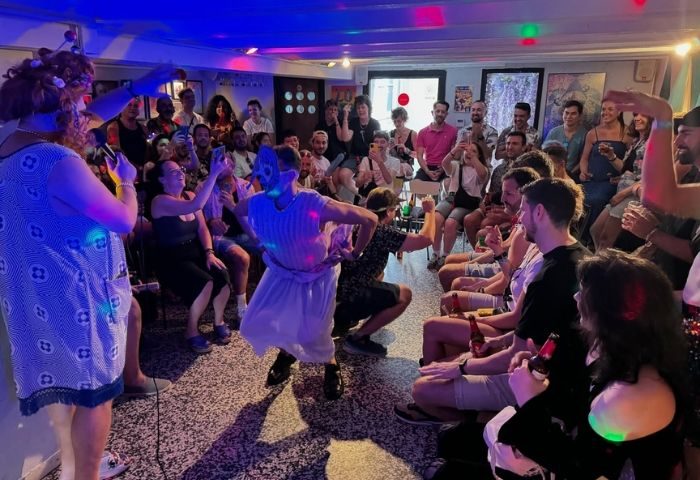 La Federica Gay Bar in Barcelona: Drag queens perform for a crowd of gay men. People are taking photos and cheering. Nightlife scene.