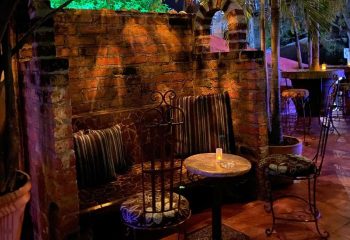 La Noche Gay Bar in Puerto Vallarta: Cozy brick seating area with pillows, chairs, and a small table. Nightlife spot for gay men's travel.