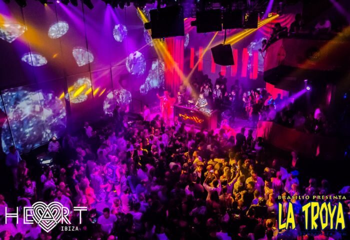La Troya at HEART Ibiza gay club. A DJ plays for a large crowd under purple & yellow lights. Gay nightlife & travel advice.