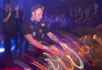 DJ at La Troya gay club, HEART Ibiza. Man mixing music in a vibrant, energetic atmosphere. Gay nightlife travel advice.