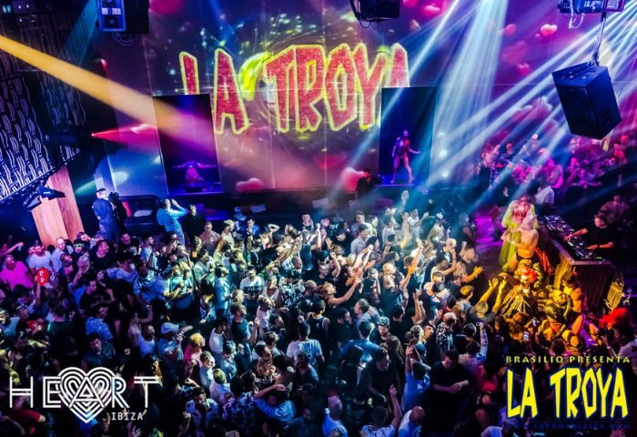 La Troya gay club night at HEART Ibiza. Crowd of men dancing, stage with performer, lights. Gay travel advice for Ibiza nightlife.