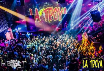La Troya gay club night at HEART Ibiza. Crowd of men dancing, stage with performer, lights. Gay travel advice for Ibiza nightlife.