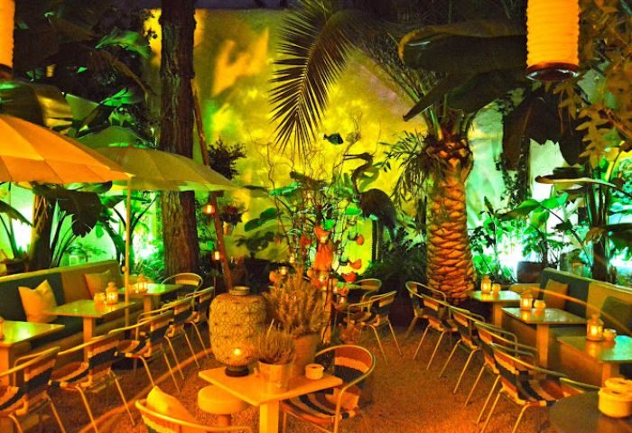 La Villa Gay Bar in Sitges: Outdoor seating area at night, lush tropical garden setting. Gay travel destination, perfect for cocktails.