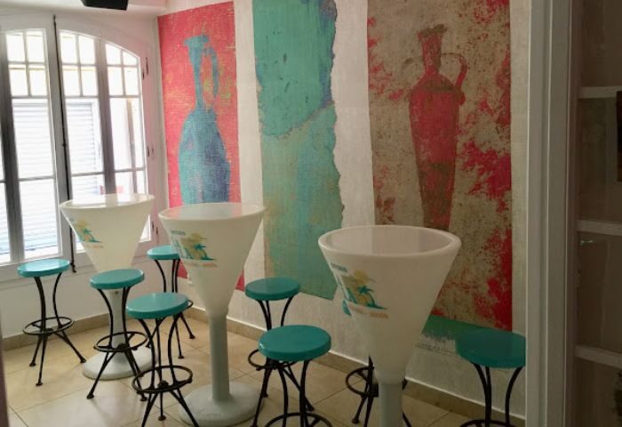 La Villa gay bar in Sitges interior. High tables, stools, and a colorful mural create a vibrant, welcoming atmosphere for gay travelers.