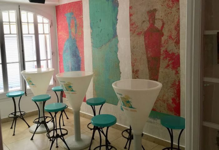 La Villa gay bar in Sitges interior. High tables, stools, and a colorful mural create a vibrant, welcoming atmosphere for gay travelers.