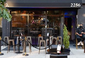Lambda Lounge, a gay bar in New York, features outdoor seating. A masked bouncer sits by the door of this LGBTQ+ friendly spot.