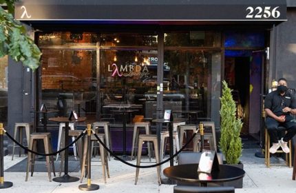 Lambda Lounge, a gay bar in New York, features outdoor seating. A masked bouncer sits by the door of this LGBTQ+ friendly spot.