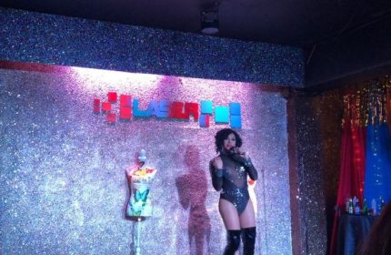 Drag queen performs at Laser Hot Bar, a popular gay bar in Cancun. Nightlife scene with stage, lights, and performer. Gay travel destination.