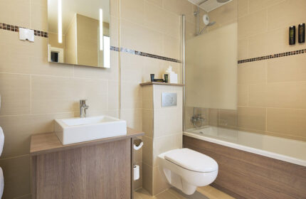 Bathroom at Hotel Turenne Le Marais, a cheap gay hotel. Features a sink, toilet, and shower/tub combo. Modern design, clean lines.