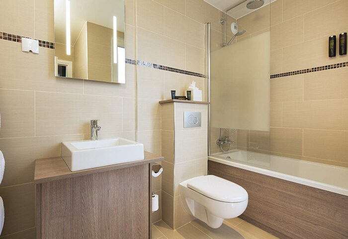 Bathroom at Hotel Turenne Le Marais, a cheap gay hotel. Features a sink, toilet, and shower/tub combo. Modern design, clean lines.