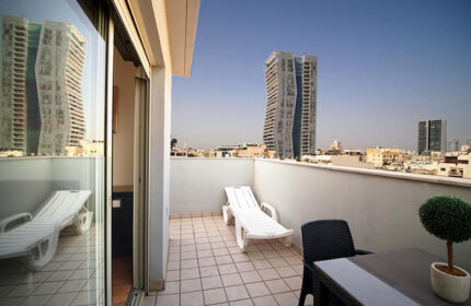 Ben Yehuda Apartments penthouse balcony view in Tel Aviv's gayborhood. Service apartment with skyline, table, chair, and lounge chair.
