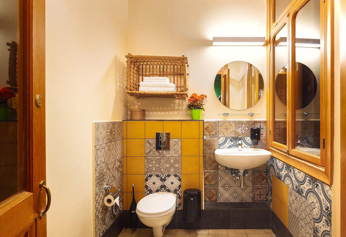 Inta Hotel Tel Aviv Jaffa bathroom. Adults Only gay hotel featuring toilet, sink, mirror, patterned tiles, and a wooden cabinet.