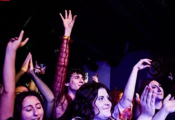 Enthusiastic crowd at Latte Fresco, Rome's gay bar. People with hands raised, enjoying the vibrant nightlife. Gay travel advice.