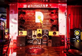 Le Date Gay Karaoke Bar stage in Montreal. Speakers, microphone, and Fireball Whisky logo. Gay travel advice, nightlife.