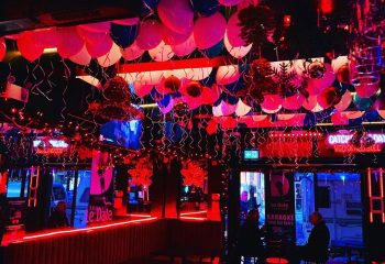 Interior view of Le Date gay karaoke bar in Montreal, featuring balloons, red lighting, and patrons enjoying the atmosphere.