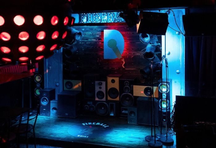 Le Date Gay Karaoke Bar in Montreal stage. Disco ball, speakers, microphones, and D logo with microphone. Gay travel advice.