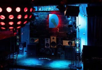 Le Date Gay Karaoke Bar in Montreal stage. Disco ball, speakers, microphones, and D logo with microphone. Gay travel advice.