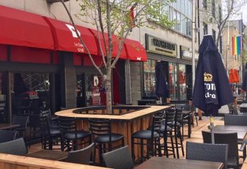 Le Date Gay Karaoke Bar in Montreal. Outdoor seating area with tables, chairs, and a tree growing in the middle of a bar.