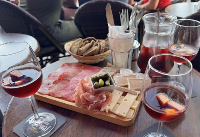 Le Mixx Gay Bar in Gran Canaria: Charcuterie board with cured meats, cheese, pickles, and bread, accompanied by glasses of red wine.